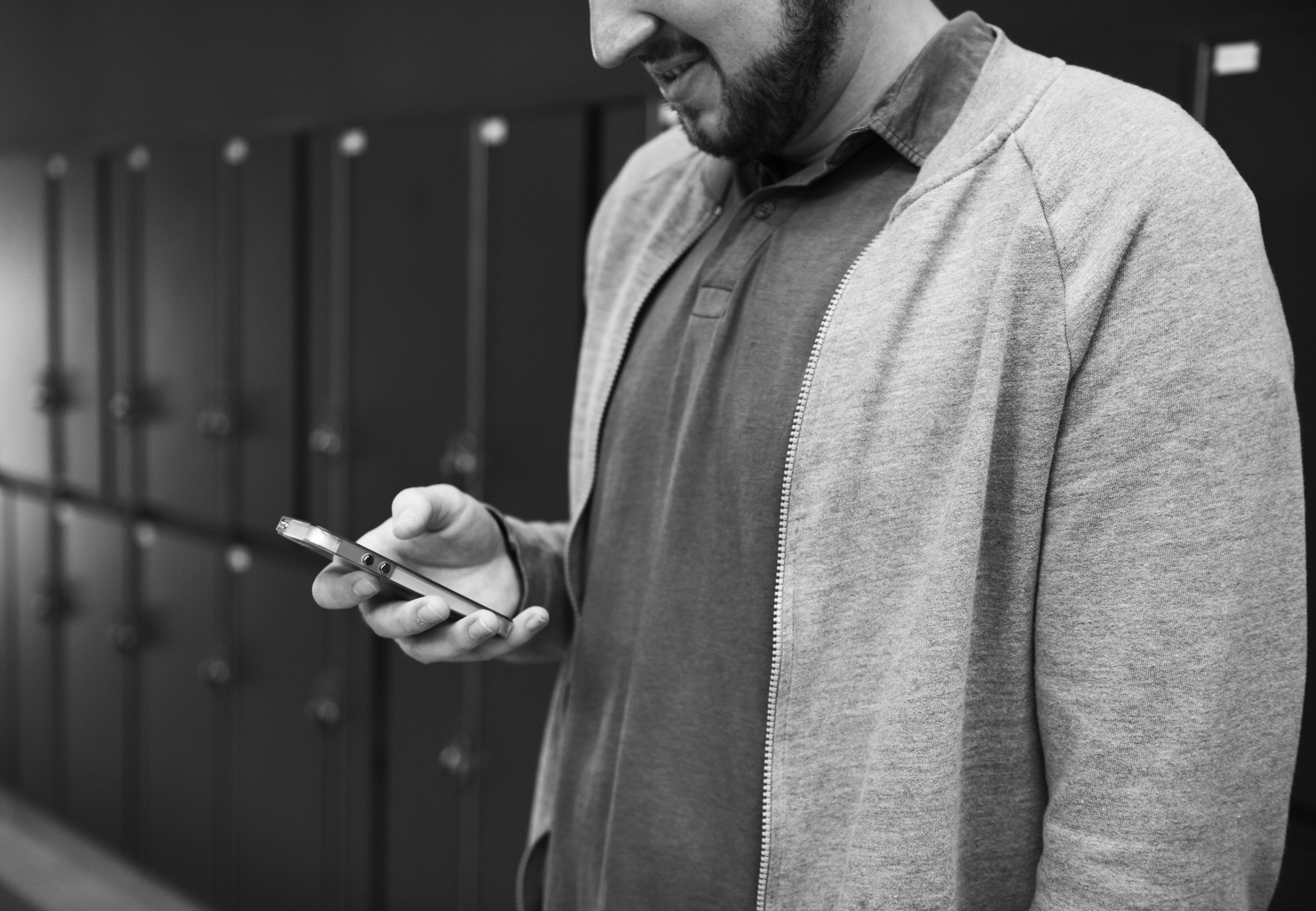 Man Standing infront of Red Locker Using Mobile Phone